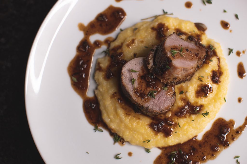 herbed pork loin with polenta and pan sauce plated top view
