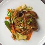 plated chicken thigh with soba noodles and vegetables top view