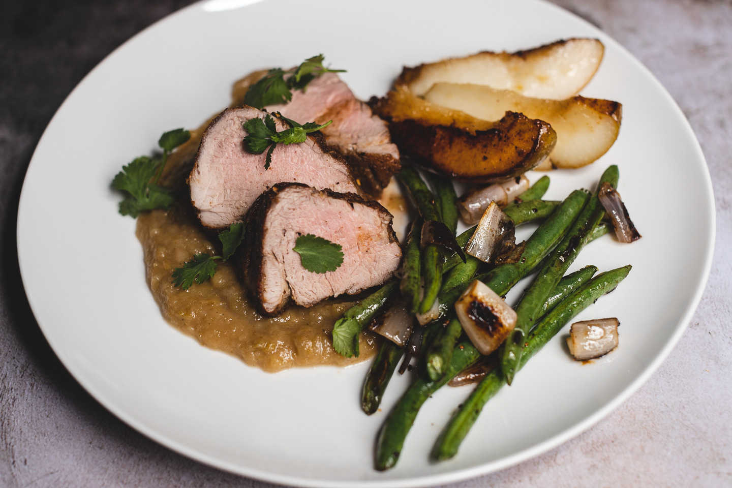 side view finished plate pork tenderloin with pear sauce green beans and shallot