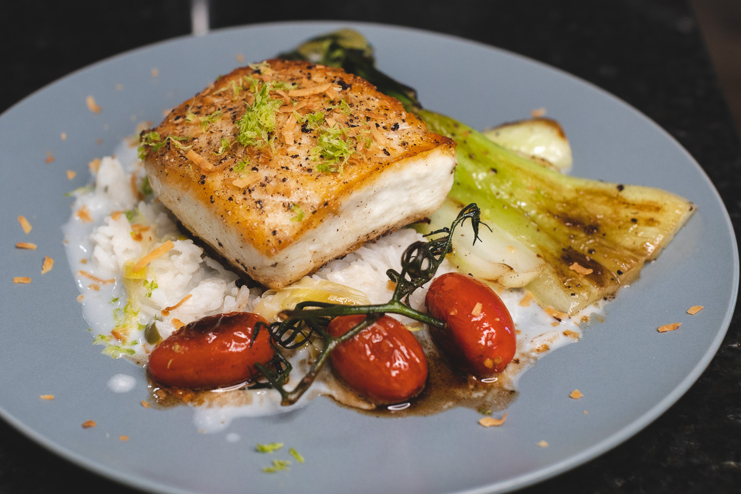 side view plated halibut with bok choy, rice, coconut milk, tomatoes