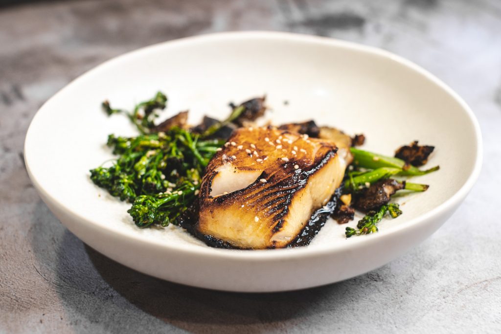 Side View Of Plated Miso Black Cod With Broccolini And Shiitake