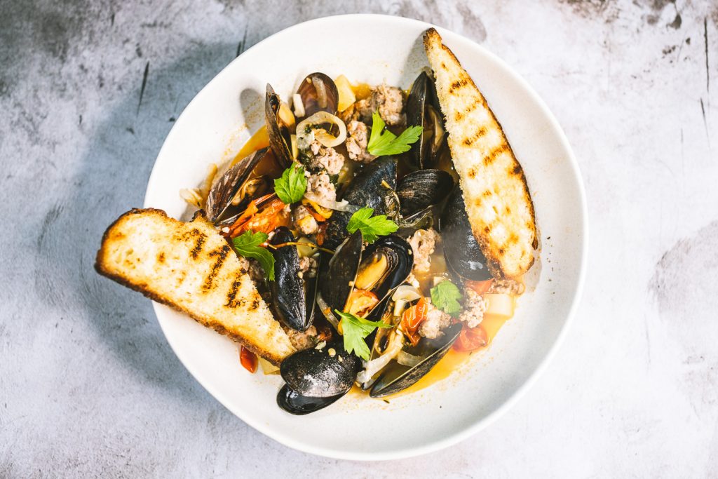 Top View Of Mussels With Italian Sausage Vegetable Broth And Crostini