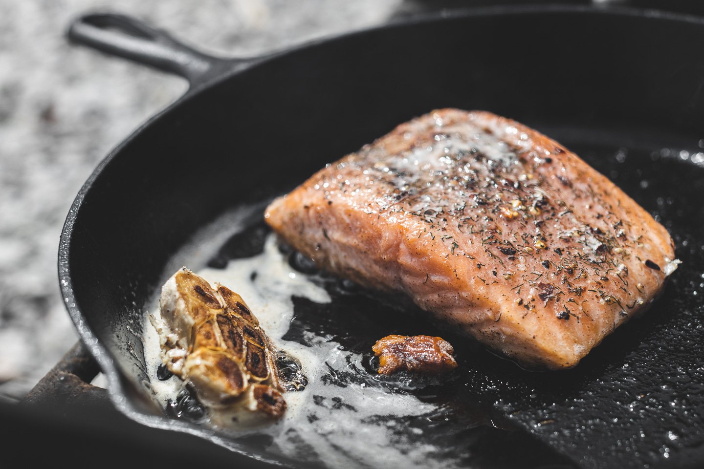 cooking salmon in lodge cast iron pan with butter and garlic [copyright david lewetag ii]